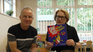 Adam and Charlotte sitting together, holding a book.