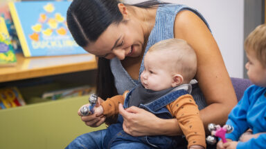 A photo of a woman and a baby with a rattle enjoying a BookTrust Storytime session